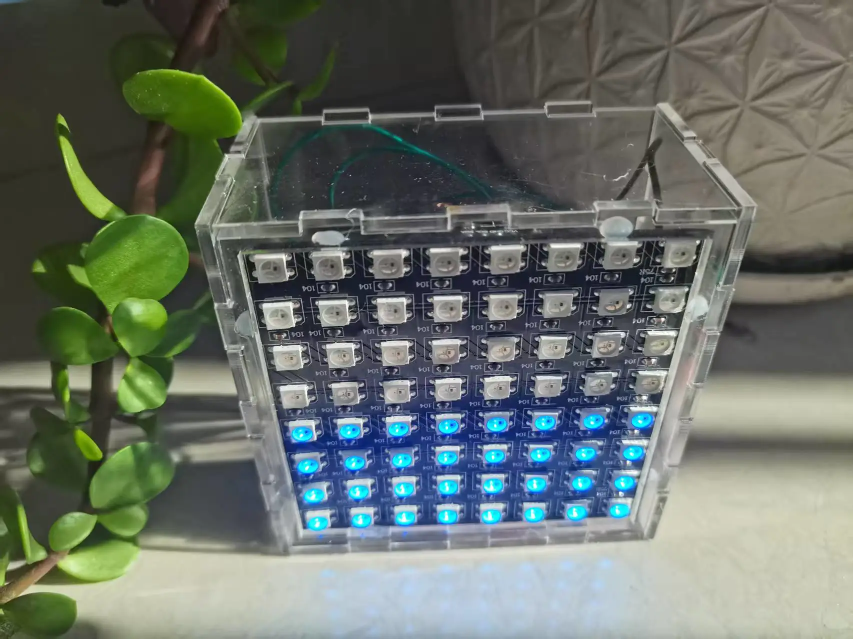 装进透明亚克力方盒的8×8 LED点阵，下半部亮起蓝色模拟半盒水位